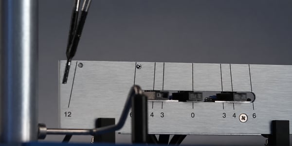 Close-up of a pendulum hardness tester, showing the pendulum arm and measurement scale